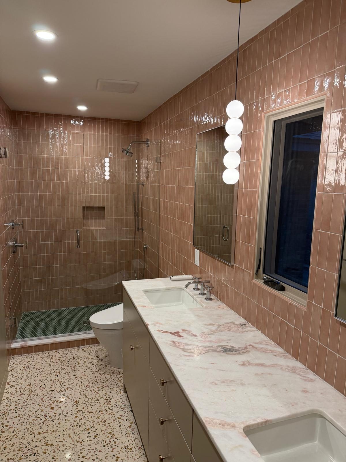 Bathroom with pink tile, marble-veined vanity, and a glass shower