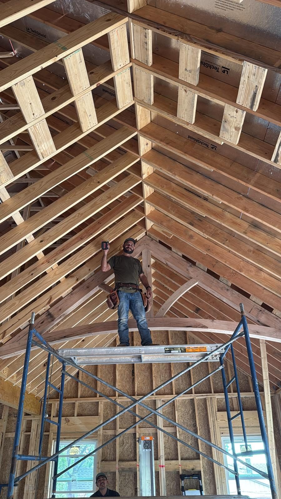 An EJ crew member standing on scaffolding inside a freshly framed cathedral ceiling