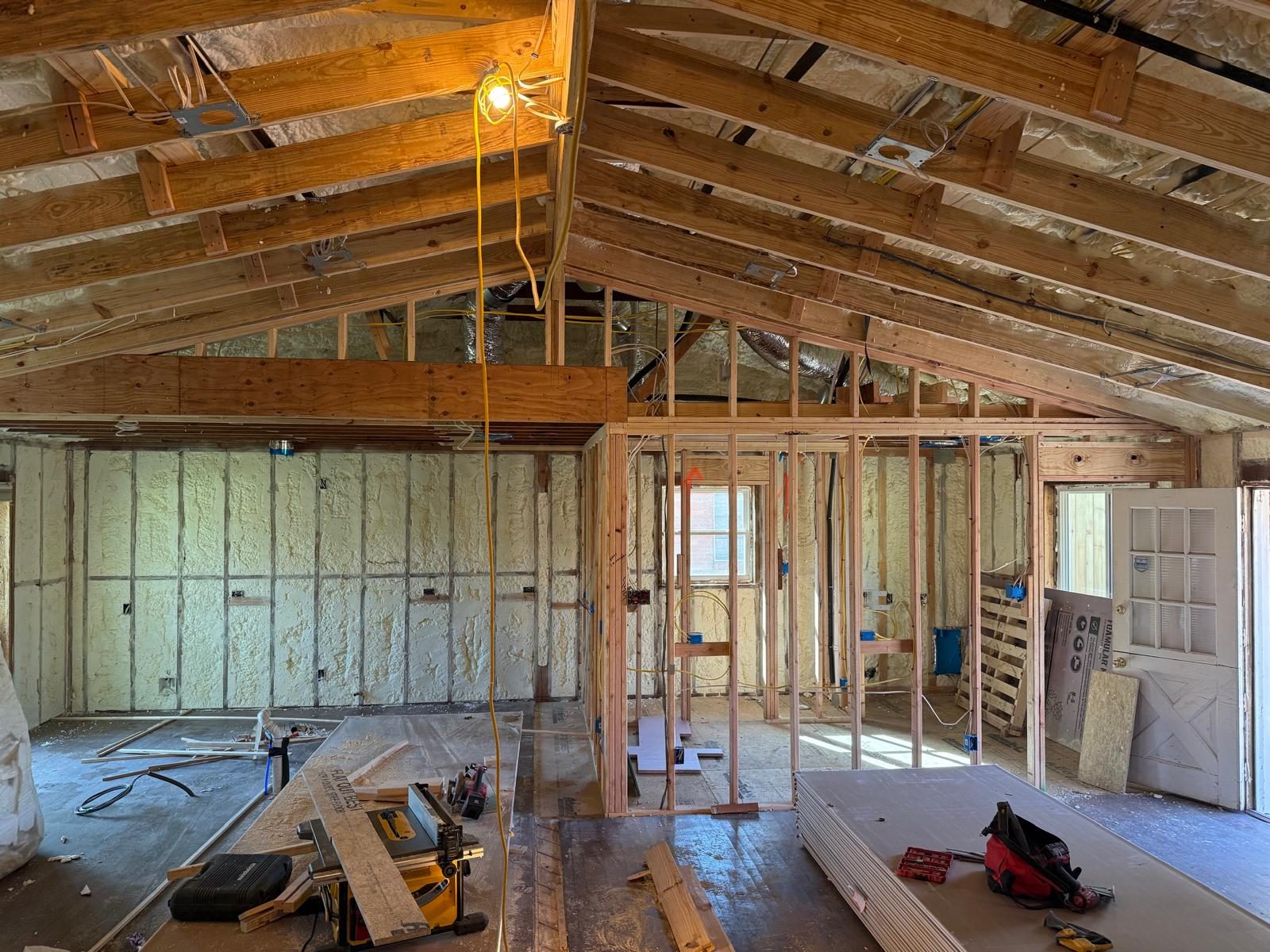 Interior framing and spray-foam insulation under a vaulted roofline