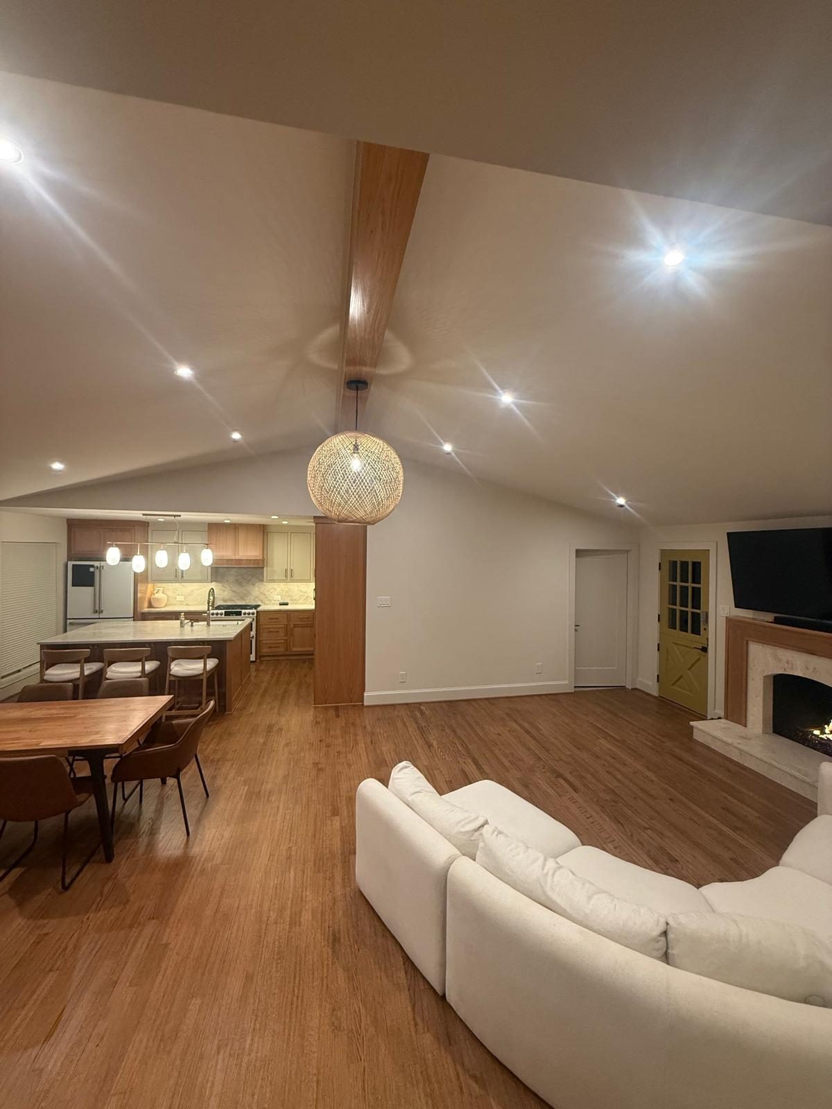 Finished open-concept living and kitchen with a white-oak beam, pendant light, and hardwood floors