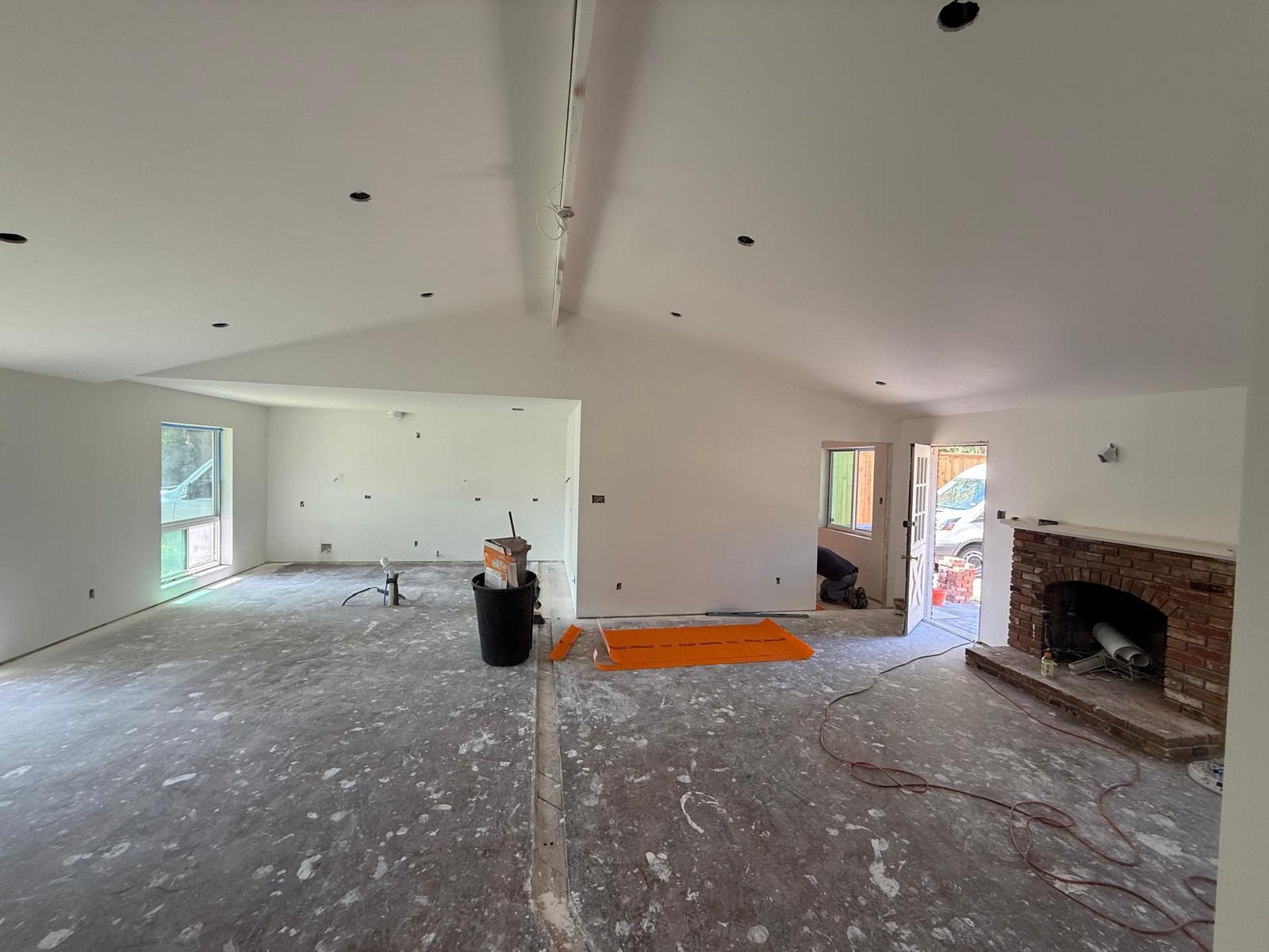 A vaulted whole-home remodel at the drywall stage, brick fireplace exposed
